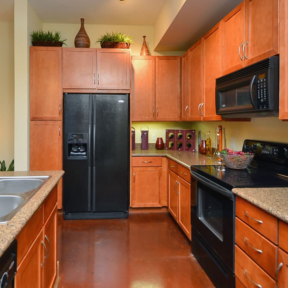 Apartments in Uptown Houston, Galleria Area A kitchen with black appliances and wooden cabinets can be found in apartments in Uptown Houston or apartments in Galleria Area.