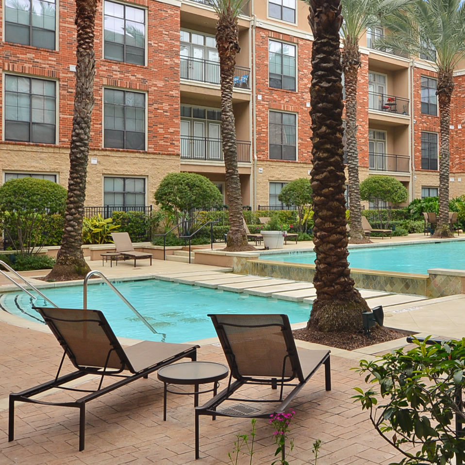 Apartments in Uptown Houston, Galleria Area An apartment complex in Uptown Houston with a swimming pool and lounge chairs.