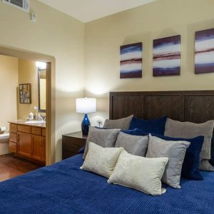 Apartments in Uptown Houston, Galleria Area An inviting bedroom with a comfortable bed adorned with a soothing blue comforter.