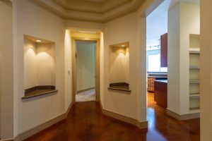 Apartments in Uptown Houston, Galleria Area A hallway with beige walls in this three-bedroom apartment leads to a room with brown floors and white shelves on the left. Two lighted alcoves are built into the walls on either side, and a door at the end is partially open. The Augusta Apartments In The Galleria Area of Houston 2660 Augusta Drive Houston, TX 77057 p: (832) 648-3088 f: (832) 675-0401