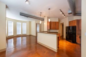 Apartments in Uptown Houston, Galleria Area Modern kitchen with wooden cabinets, granite countertops, black appliances, and industrial-style exposed ducts. This three-bedroom apartment features an adjacent room with large windows, blinds, and glossy hardwood floors. The Augusta Apartments In The Galleria Area of Houston 2660 Augusta Drive Houston, TX 77057 p: (832) 648-3088 f: (832) 675-0401